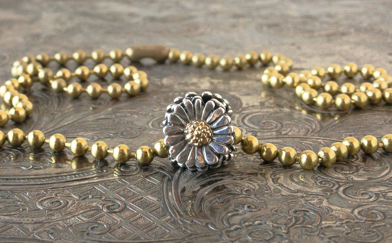 Trollbeads sterling silver and 18 karat gold "Daisy" bead on a gold-toned ball chain necklace.