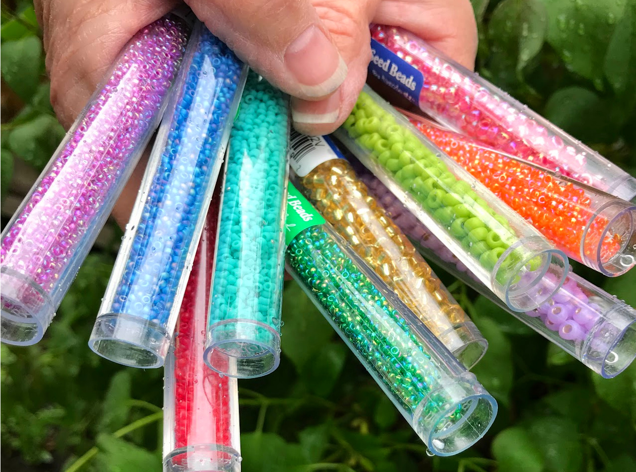 A bunch of tubes of colourful seed beads being held like a bouquet of flowers.