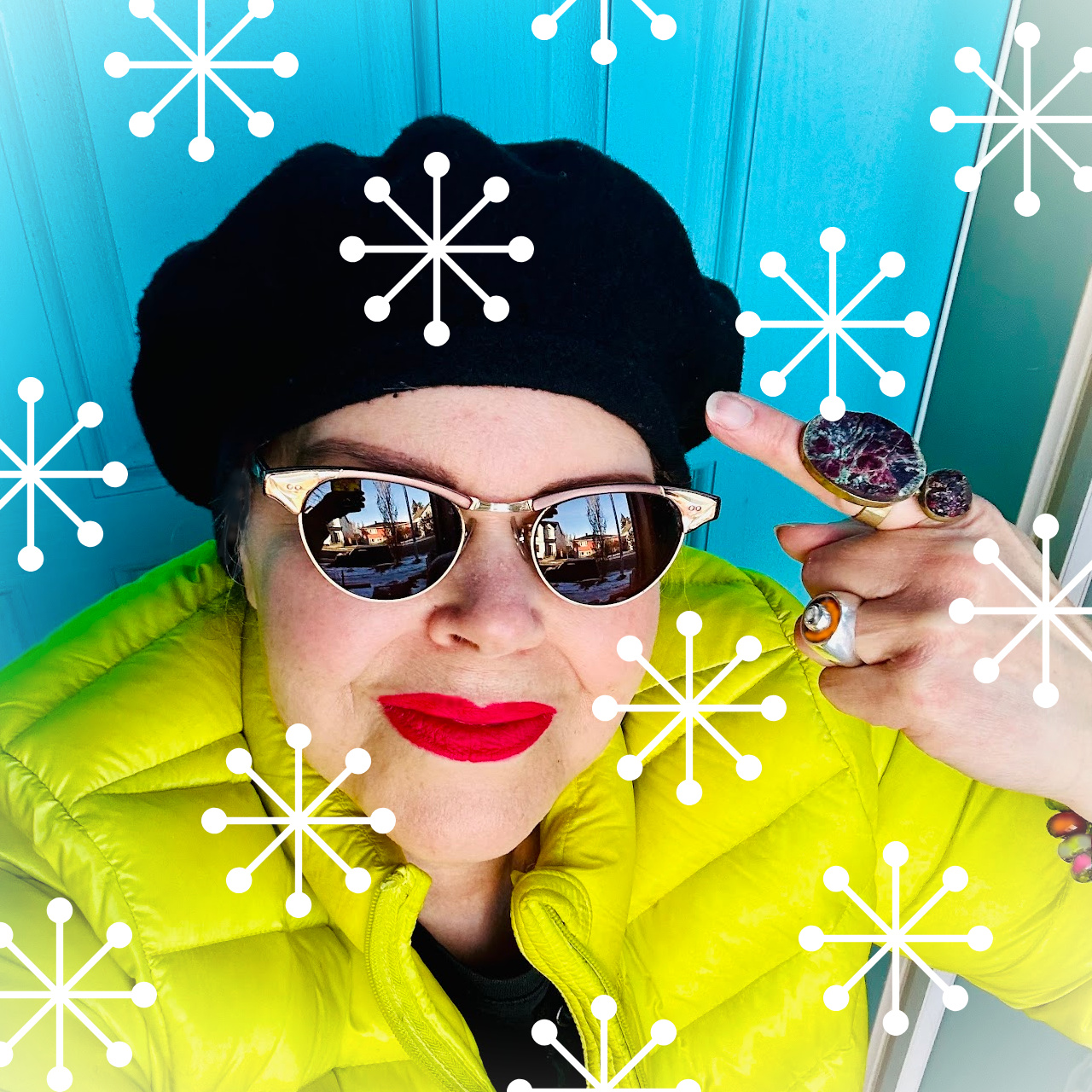 Woman wearing a black beret and a bright coloured jacket, with white snowflakes overlayed on the image